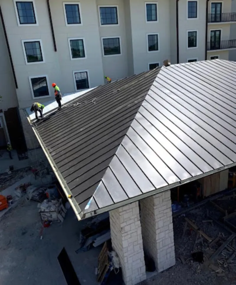 Crew installing standing seam metal roof panels on a commercial project in Norway